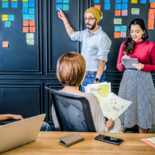 a group of people in a boardroom with sticky notes on a board