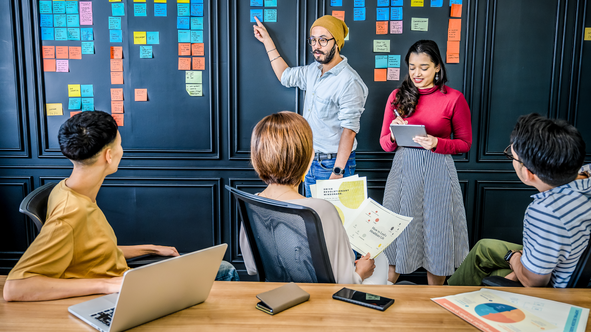 a group of people in a boardroom with sticky notes on a board