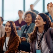 Woman in crowd raising her hand | What is employee engagement?